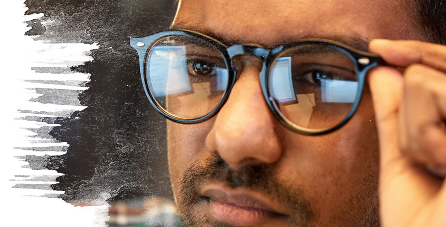 Close up of a mans face as he adjusts his glasses